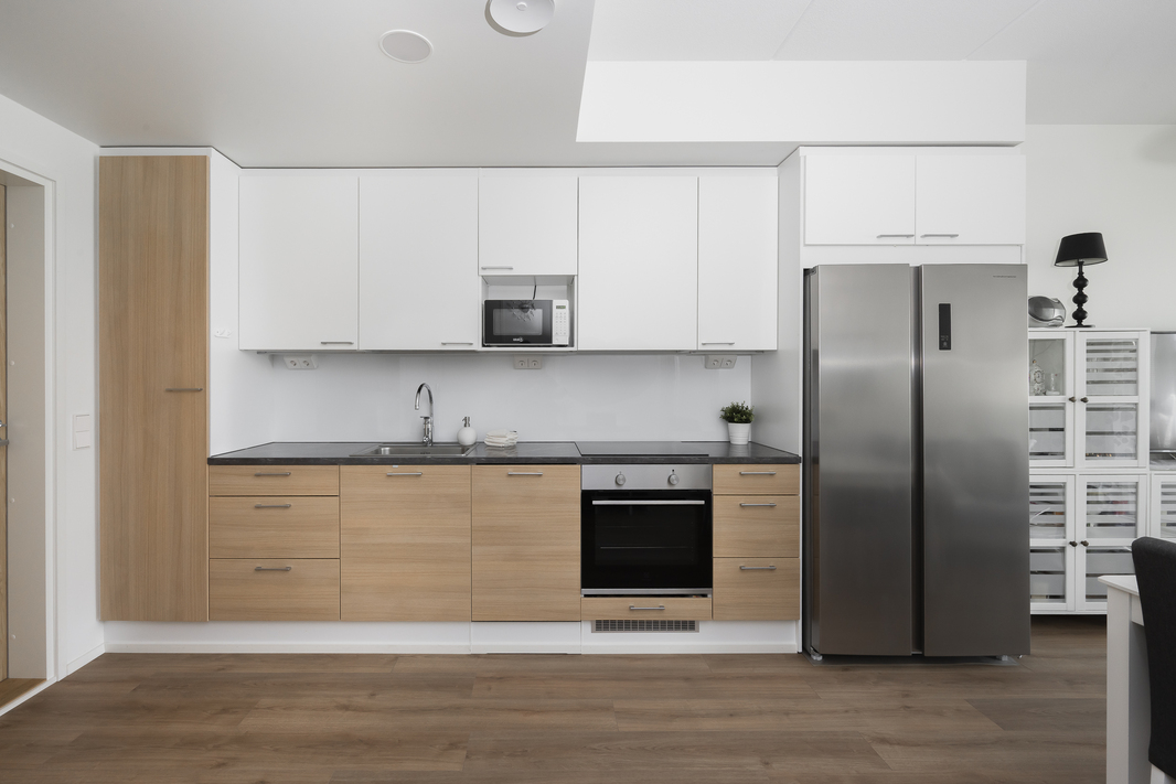 Keittiössä integroitu astianpesukone, induktioliesi, erillisuuni ja side-by-side jääkaappipakastin.