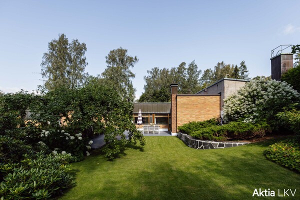 Piha, kivetys oikealla ja kukkivia pensaita
